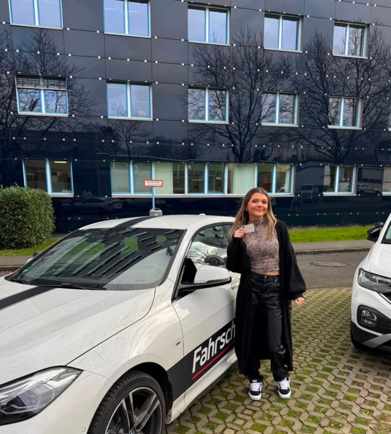 Mia mit ihrem Führerschein vor einem Auto des Fahrschulzentrums Kassel